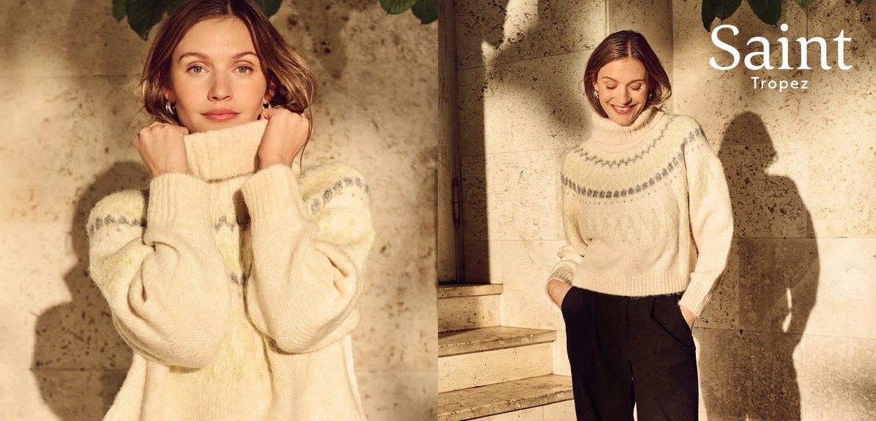 Ivory sweater with a high collar and loose fit, featuring blue and green patterned accents. Textured knit fabric enhances warmth.