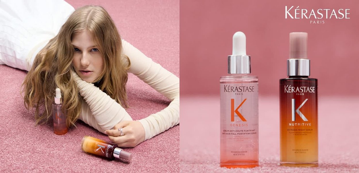 Kérastase-hårplejeprodukter på en pink overflade: glasflasker med hvide og sølvfarvede detaljer. Den ene indeholder et klart serum; den anden har en gradient farve.