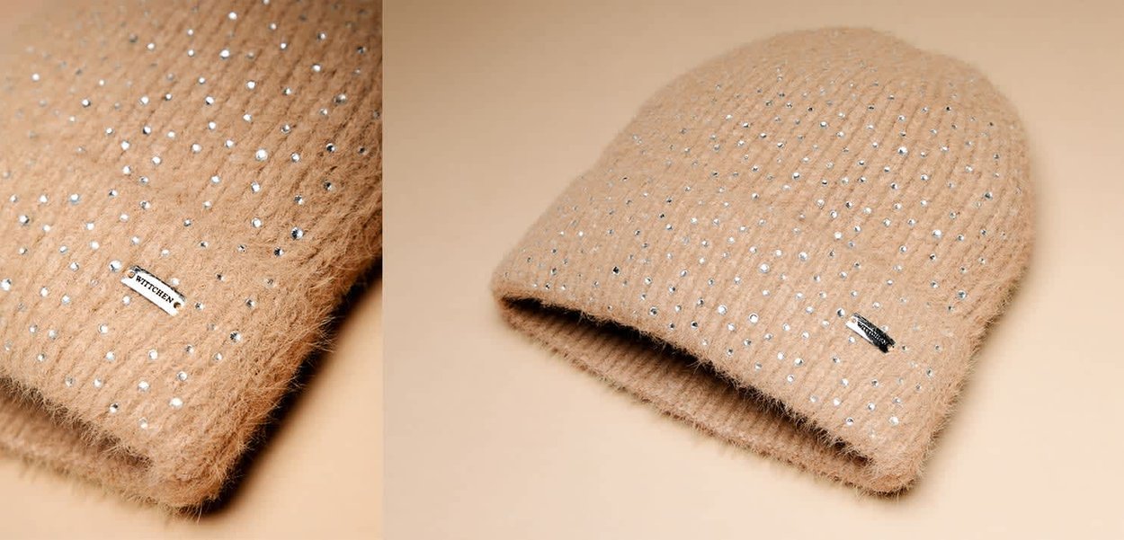 Beżowa wełniana czapka z miękką, puszystą fakturą, ozdobiona srebrnymi elementami i małą metką logo z boku.