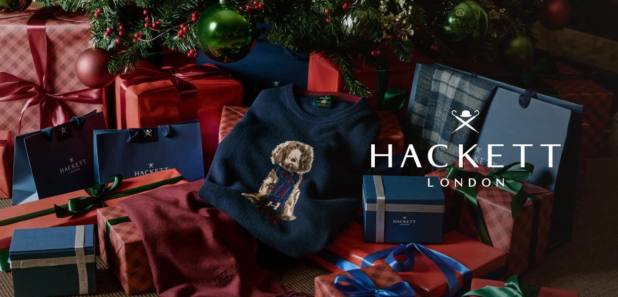 Suéter azul marino con un bordado de perro, acompañado de una bufanda burdeos, rodeado de regalos envueltos en colores vivos bajo un árbol de Navidad.