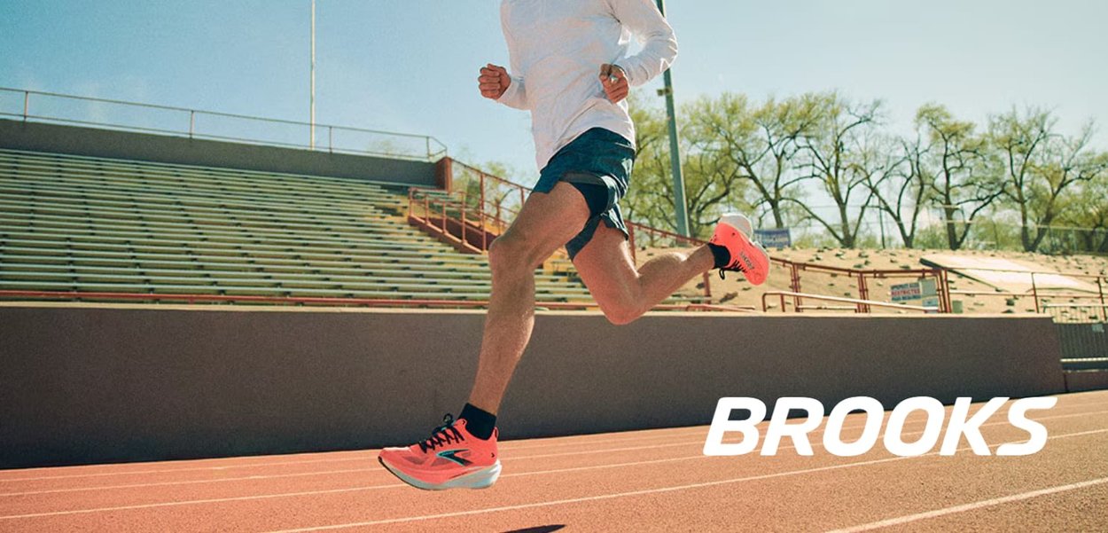 Des chaussures de course roses vives avec des accents noirs, des vêtements de sport en tissu léger, et une surface de piste lisse dans un stade extérieur ensoleillé.