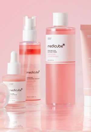 Four skincare products in pink bottles: a serum with a dropper, a toner, a mist, and a cream, featuring sleek designs and minimal text.