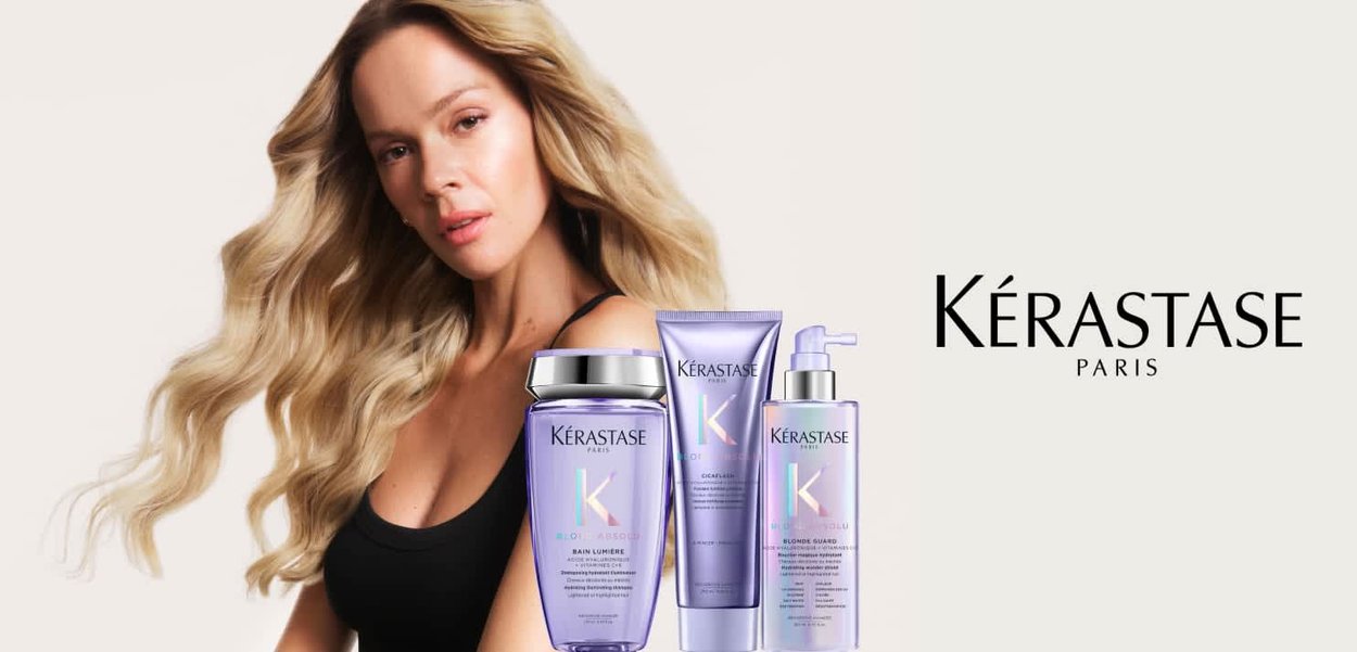 Mujer con cabello largo y rubio junto a tres productos de cuidado capilar Kérastase con aroma a lavanda y el logo de Kérastase Paris sobre fondo blanco.
