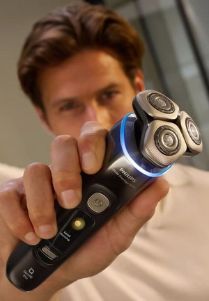 Philips 9000 Prestige Ultra elektrische scheerapparaat met een zwarte behuizing, drie ronde mesjes, een blauwe LED-verlichting en bedieningsknoppen.