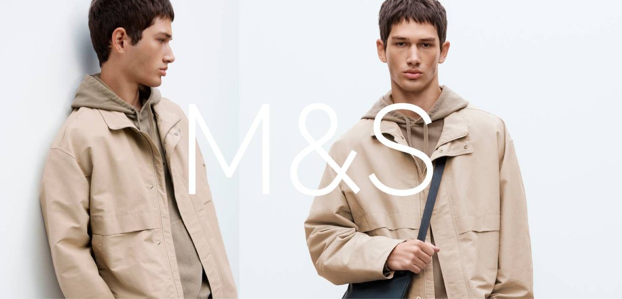 Beige Jacke mit Kapuze, aus weichem Stoff. Mit Druckknopfleiste vorne und Taschen-Details. Das Modell trägt eine dunkle Umhängetasche.