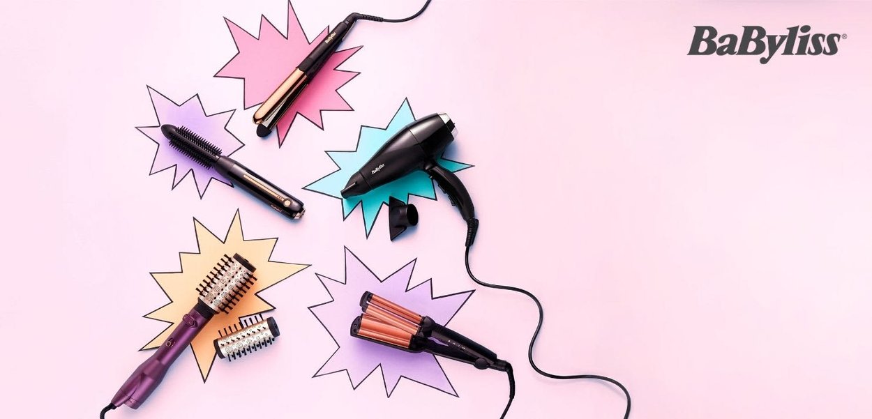 BaByliss hårstylingsverktøy på rosa bakgrunn: svart hårføner, krølltang, varmebørste og tupper i forskjellige former, med svarte og lilla detaljer.