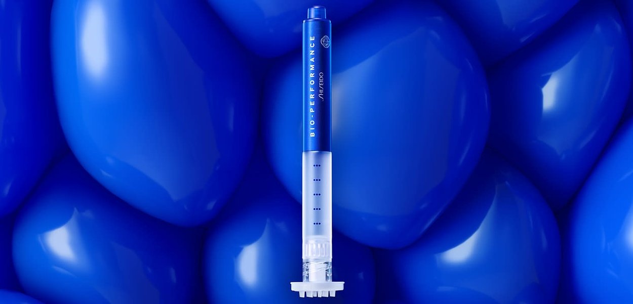 Tubo applicatore per skincare blu con sezione inferiore trasparente, marcature graduated e branding dettagliato. Ambientato su uno sfondo blu texturizzato.