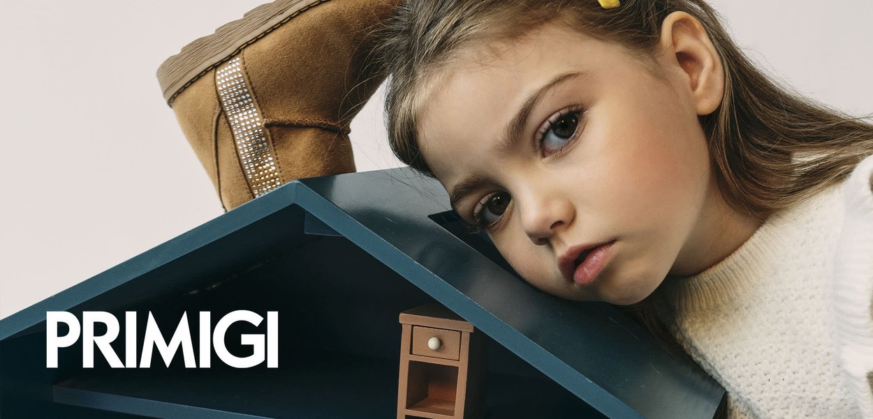 Dollhouse features blue exterior, three levels, wooden furniture, including rocking chair, cabinet, and decor items..child resting on it.