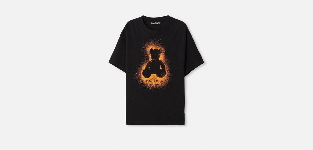 Maglietta nera di cotone a maniche corte con grafica di un orso arancione e la scritta "BEAR IN MIND" stampata in stile consumato.