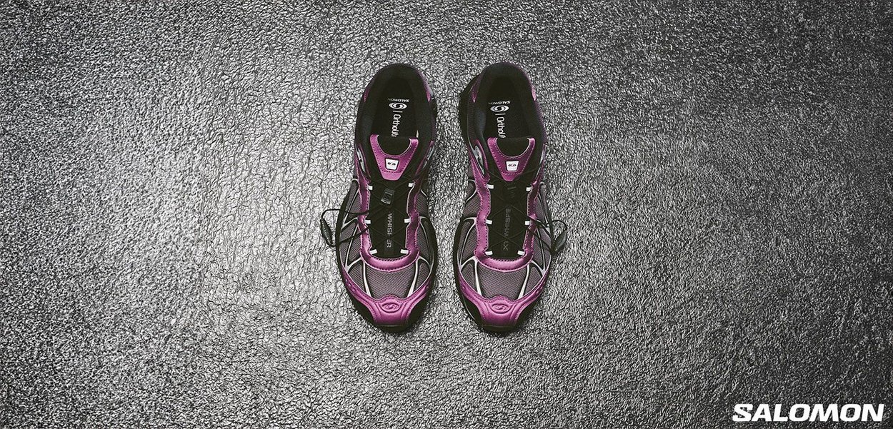 Scarpe da corsa viola e nere con una tomaia in mesh traspirante, vestibilità aderente e suola in gomma. Presentano lacci sottili e una soletta ammortizzata.