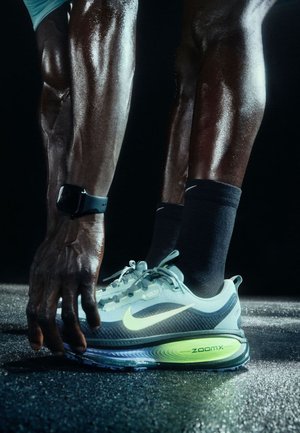 Nike ZoomX Laufschuh in Hellblau und Grün, mit einem strukturierten Mesh-Obermaterial, dicker Sohle und auffälligem "ZoomX"-Branding.