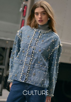 Light blue denim jacket with pearl embellishments and diamond stitching. Features button closure and two front pockets.