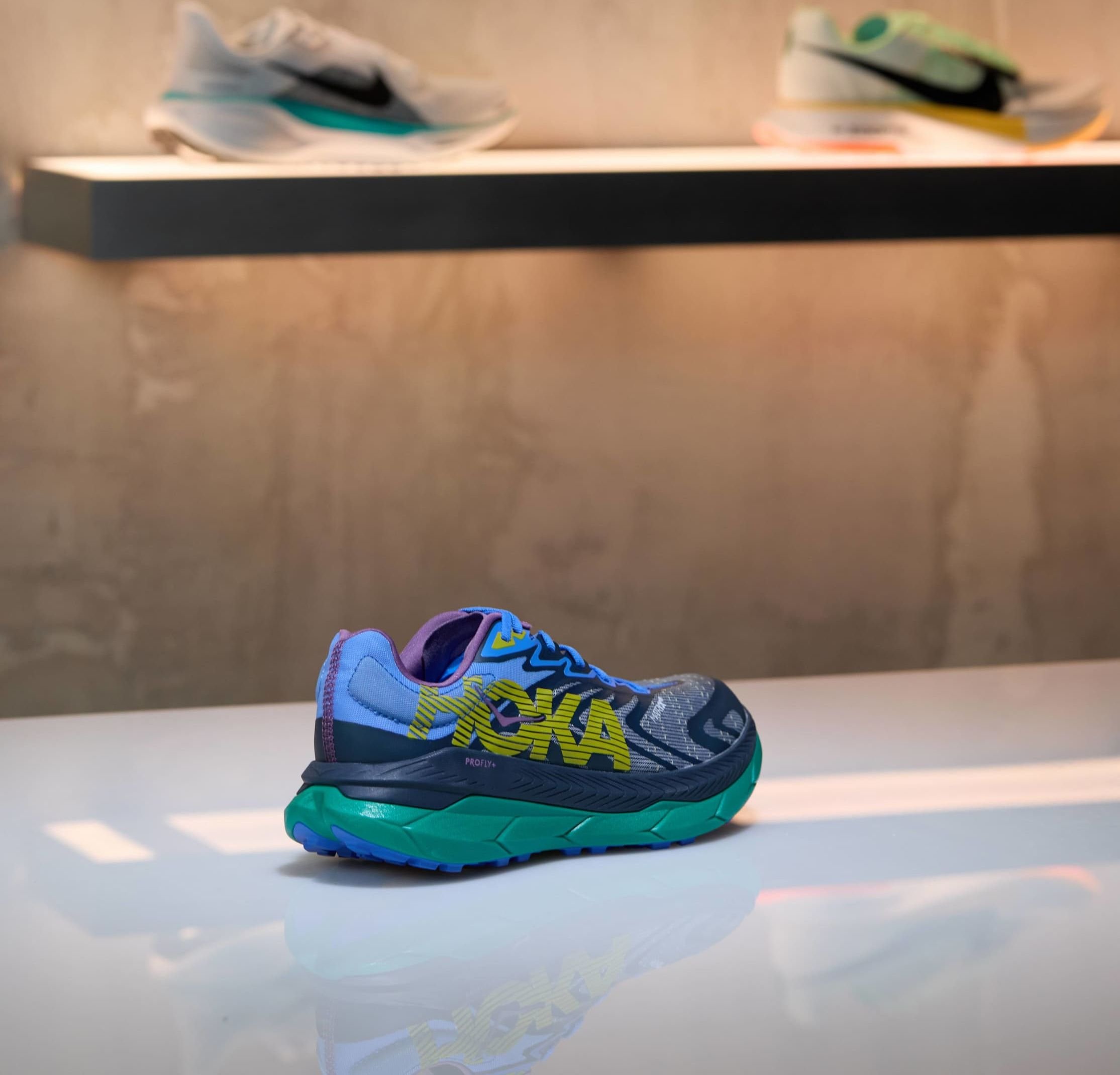 Laufschuh mit blau-grünem Farbschema, atmungsaktivem Obermaterial, markantem gelben Logo und texturiertem Sohlenprofil für guten Halt. Verfügt über einen gepolsterten Schuhkragen.