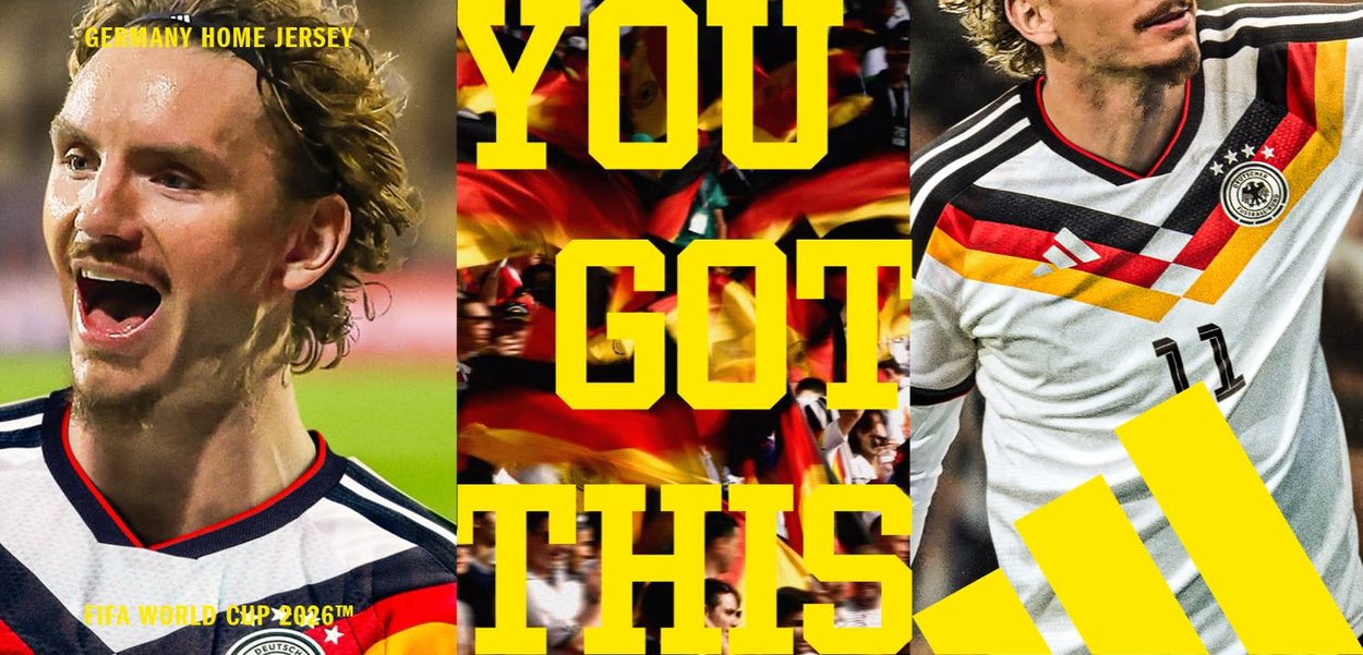 Zwei Fußballspieler, die das Heimtrikot Deutschlands für die FIFA-Weltmeisterschaft 2026 mit schwarzen, roten und gelben Streifen tragen, während Fans deutsche Flaggen schwenken.