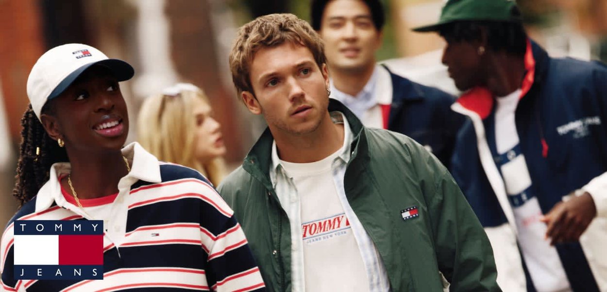 Grupa młodych dorosłych ubranych w casualowe ubrania marki Tommy Jeans, spacerujących na ulicy miasta z skoncentrowanymi wyrazami twarzy.