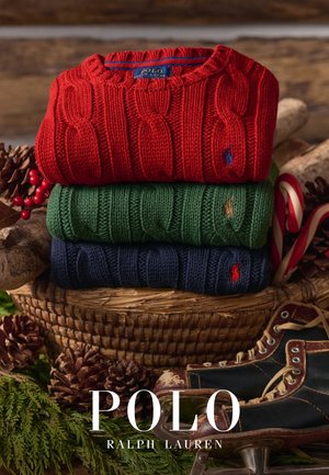 Pila de tres suéteres tejidos: rojo, verde y azul marino. Cada uno presenta un diseño de punto trenzado y un pequeño logo de polo bordado en el pecho.