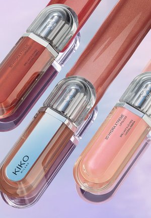 Quattro lip gloss KIKO Milano 3D Hydra Xtreme in tonalità nude, rosa e corallo con tappi trasparenti e arrotondati su una superficie viola.