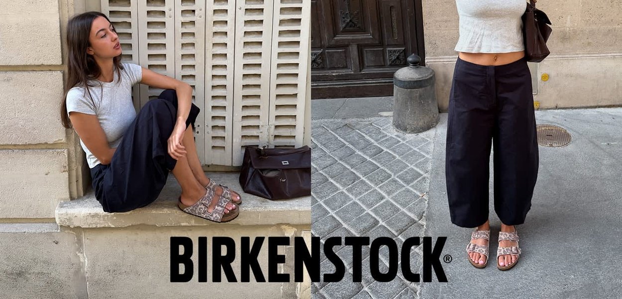 Frau trägt schwarze Hose und graues Oberteil, sitzt und steht im Freien und zeigt Birkenstock-Sandalen mit zwei verstellbaren Riemen.