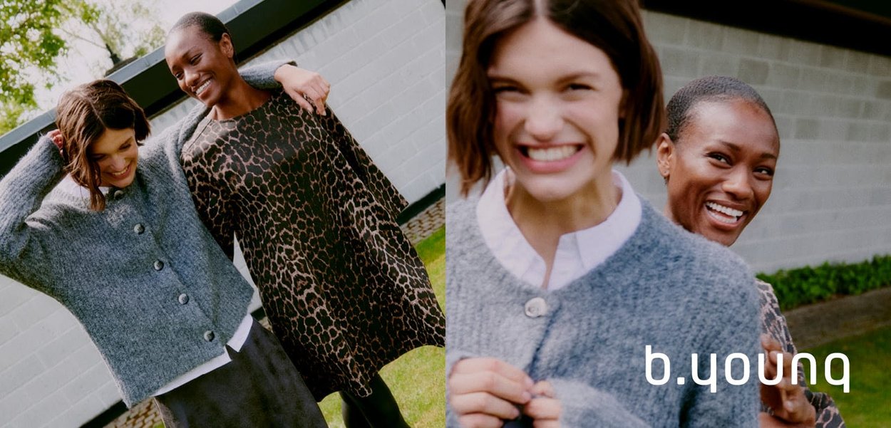 Due donne posano all'aperto. Una indossa un cardigan grigio morbido e con bottoni; l'altra un vestito a stampa leopardata. L'ambientazione è verde e luminosa.