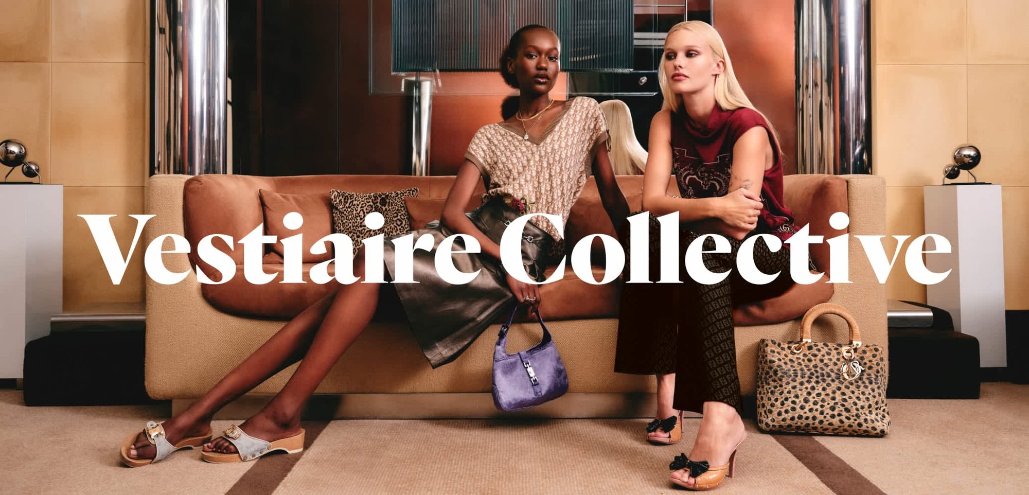 Deux femmes sont assises sur un canapé beige, l’une tenant un sac à main violet, l’autre avec un sac à motif léopard posé par terre, dans un salon moderne.