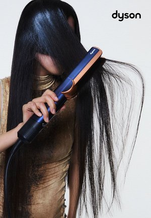 Strumento per capelli Dyson con un elegante corpo blu scuro e dettagli in rame. Capelli lunghi, dritti e lucenti di colore nero acconciati con il dispositivo.