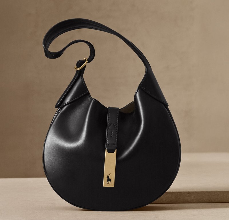 Sac en cuir noir avec une forme incurvée de style hobo. Il présente un accent en métal doré rectangulaire et une seule bandoulière ajustable.