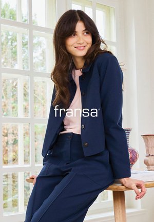 Marineblaues Sakko mit kurzem Schnitt, zwei Knöpfen und glatter Textur, kombiniert mit einem hellrosa Oberteil und passenden Hosen.