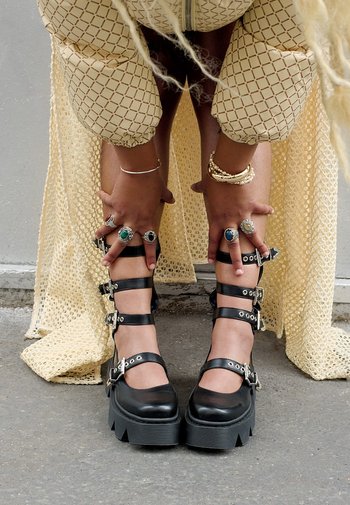 Zwarte platform schoenen met meerdere verstelbare banden, zilveren hardwareaccenten en een gestructureerde zool, aangevuld met een ribbelontwerp bij de tenen.