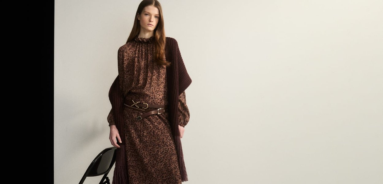 Leopardmuster-Kleid in Brauntönen, mit rüschigem Kragen und langen Ärmeln, kombiniert mit einem dunkelbraunen, taillierten Cardigan und Details aus Leder.