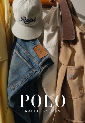 Gorra blanca de béisbol con "Ralph" en azul, vaqueros de mezclilla con etiqueta Polo y chaquetas beige y blancas colgadas en un perchero de madera.