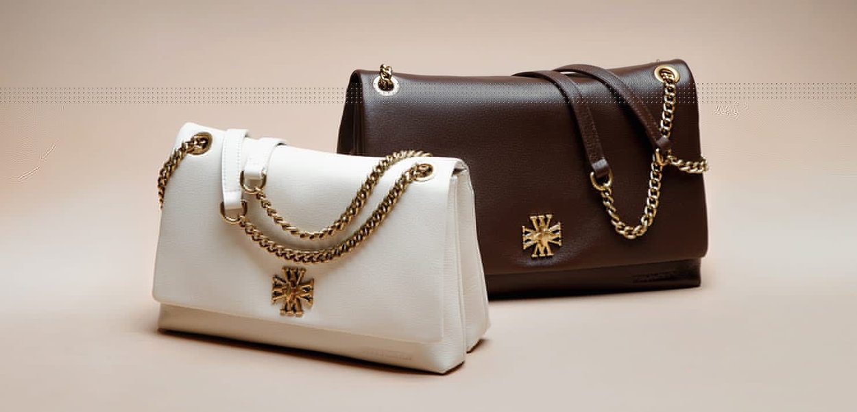 Dwie skórzane torebki, jedna biała, a druga ciemnobrązowa, z złotymi łańcuchami i ozdobnymi złotymi emblematami na neutralnym tle.