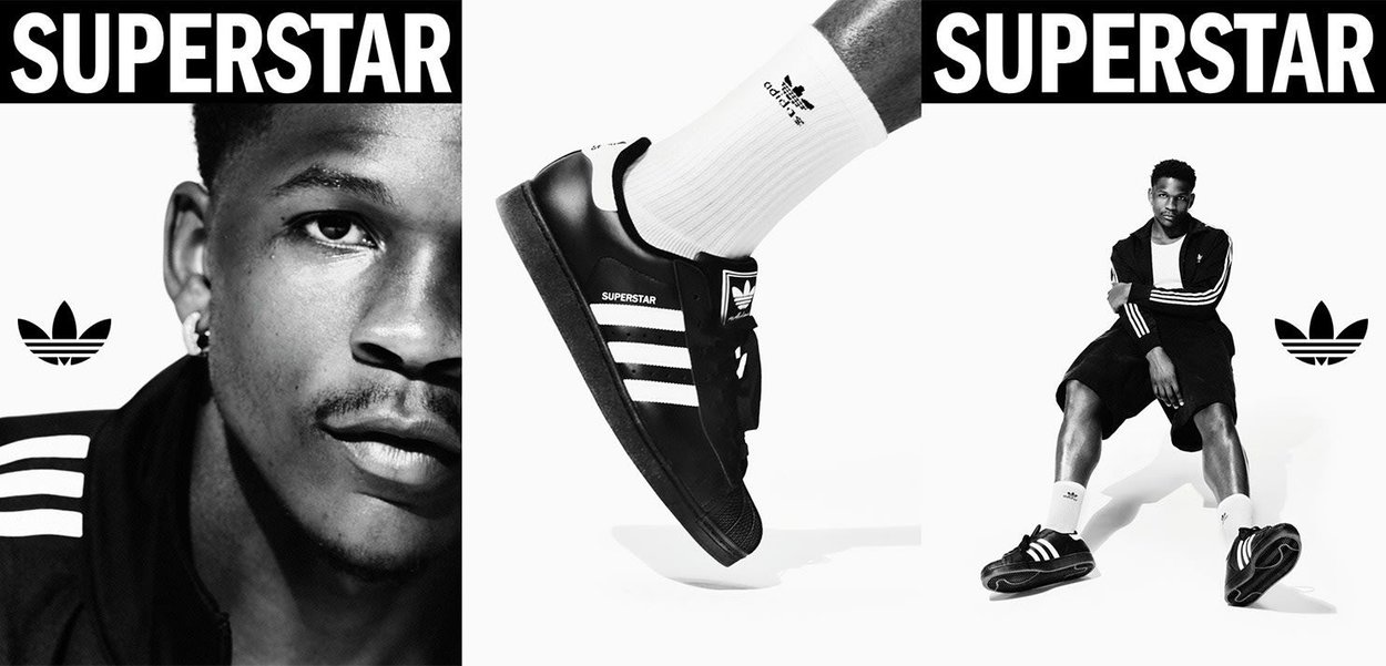 Nero Adidas Superstar con strisce bianche. Insieme a un modello in tuta nera e calze bianche. Inclusa una forte marca.