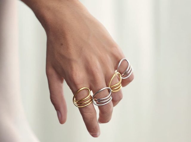 Τέσσερις δαχτυλίδια σε διάφορα σχέδια: δύο χρυσά και δύο ασημένια. Κάθε ένα έχει ομαλή, στρογγυλή μορφή με επίπεδες ζώνες, παρουσιάζοντας διακριτές υφές.