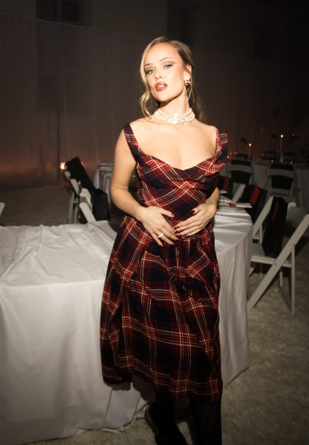 Röd och marinblå rutig klänning med figurnära överdel och utsvängd kjol. Har en fyrkantig urringning och breda axelband, kompletterad med ett pärlhalsband.