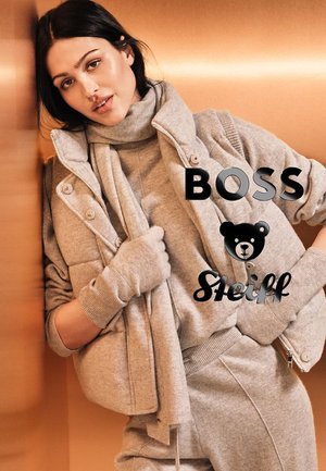 Grauer gestrickter Pullover, passende Hose und eine steppbare Weste. Das Ensemble hat einen hohen Kragen und gerippte Bündchen, mit einem Bärenlogo-Detail.