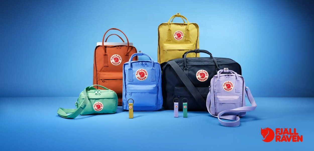 Fjällräven ryggsäckar i olika färger: orange, gul, grön, blå, svart och lila. Funktioner inkluderar logotyper, dragkedjor och remmar; texturerad tyg.