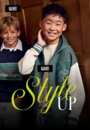 Zwei lächelnde Jungen tragen lässige Collegejacken und stehen vor einer Holzwand mit dem Text "Style Up" als Überlagerung.