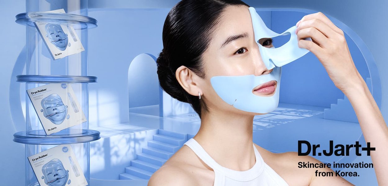 Un masque facial en caoutchouc bleu étant appliqué sur le visage d'une femme ; emballage empilé dans des contenants transparents ; texture douce et lisse ; design épuré.