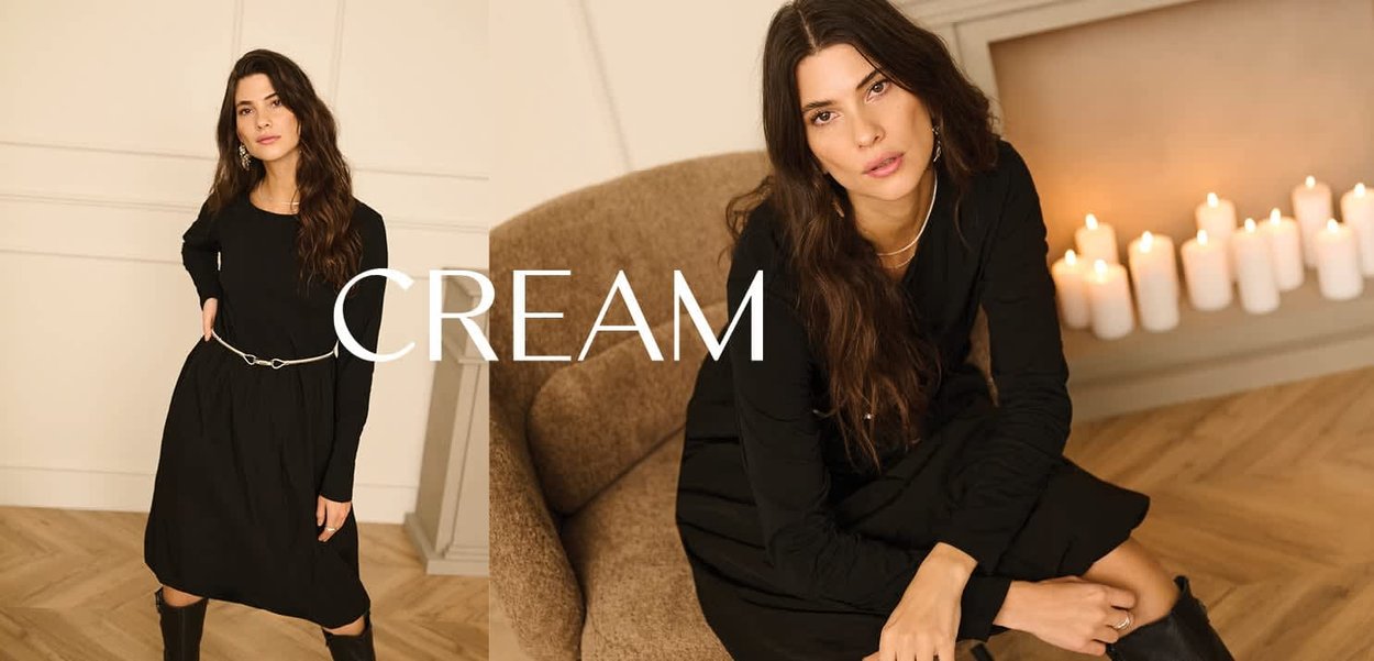 Schwarzes langärmliges Kleid mit gerafftem Rock, in der Taille mit einem silbernen Gürtel geschnürt. Modell posiert mit kniehohen schwarzen Stiefeln.