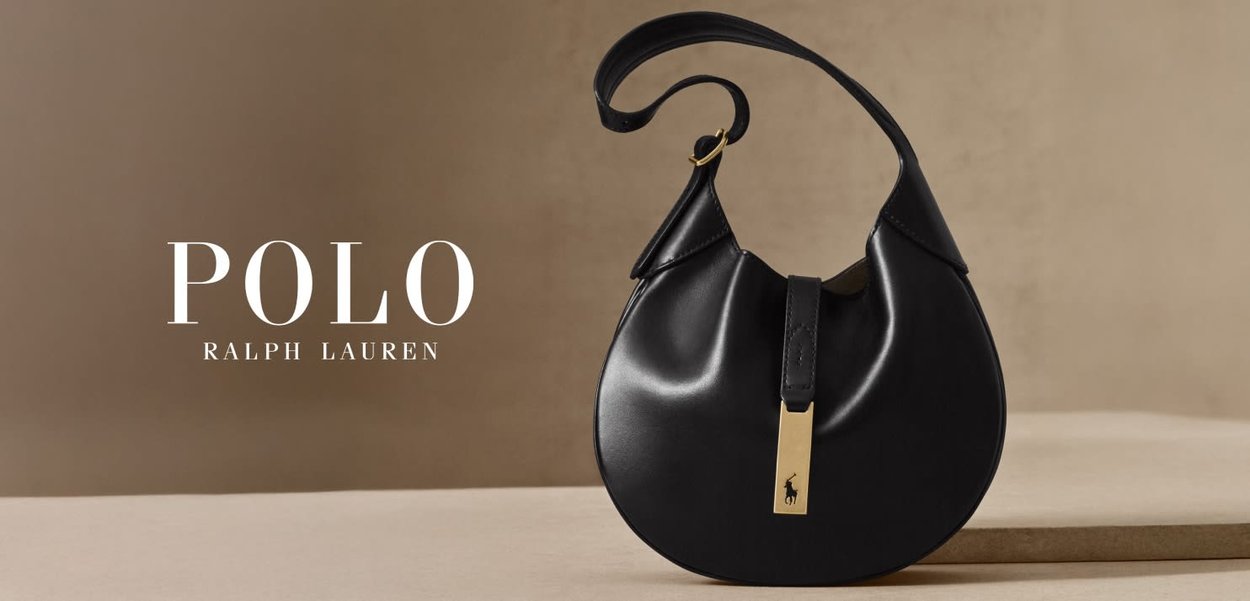 Sac à main en cuir noir de forme arrondie, avec une courte bandoulière et un accent doré arborant un petit logo à l'avant.