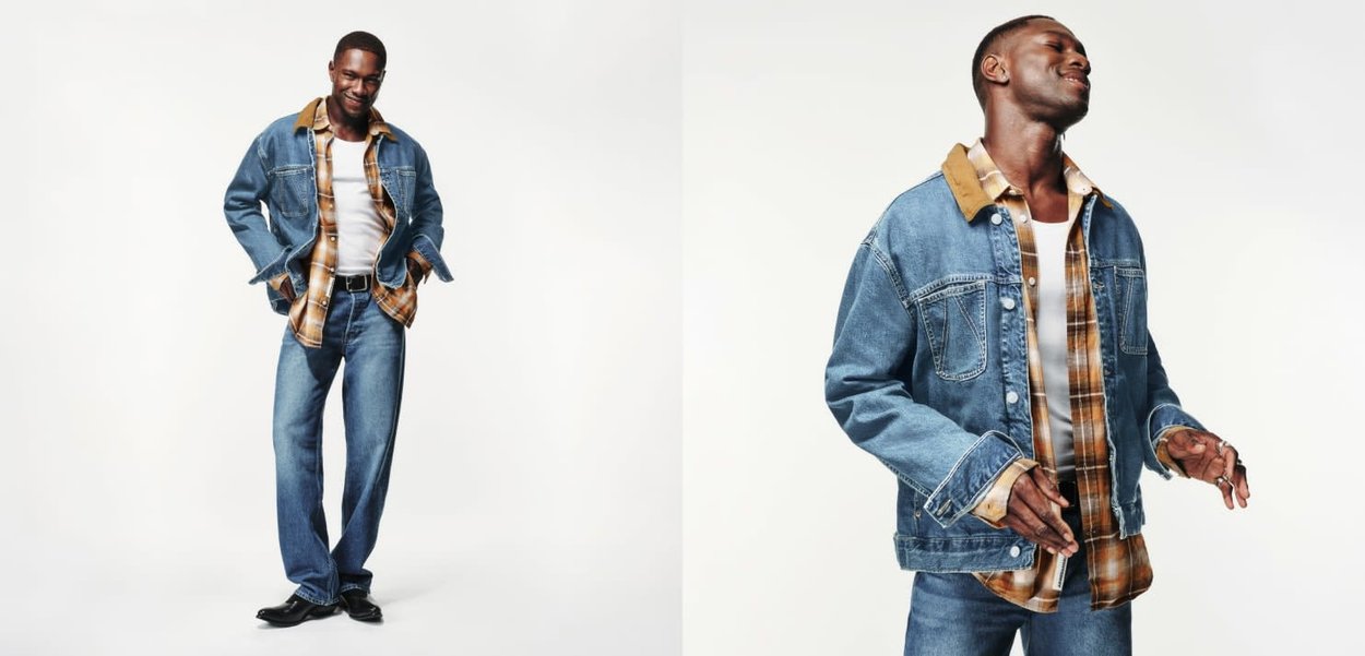 Eine Jeansjacke mit einem beigen Kragen, über einem karierten Hemd getragen. Dazu blaue Jeans, Freizeit-Schuhe und eine lockere Passform, die das Outfit abrundet.