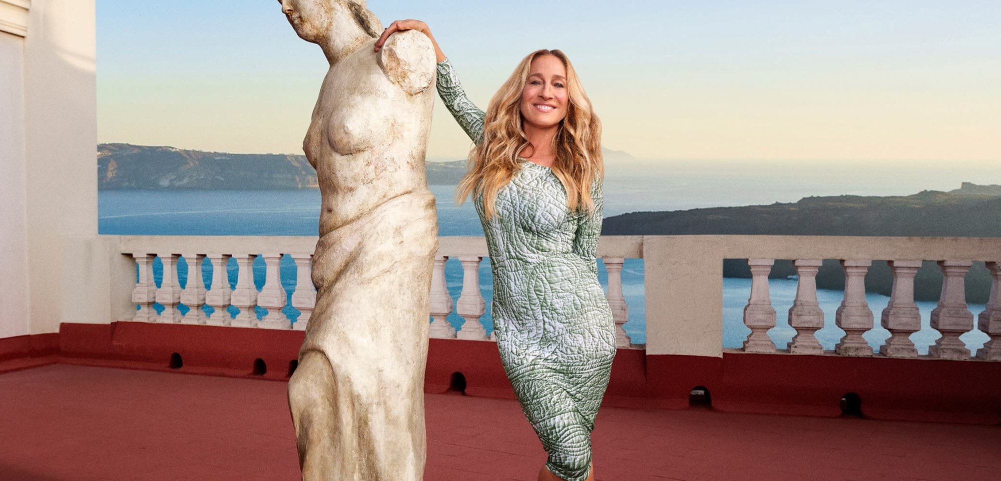 Vestido de manga larga en verde con patrones de hojas texturizadas, silueta ajustada, usado al lado de una estatua de piedra contra un fondo escénico.