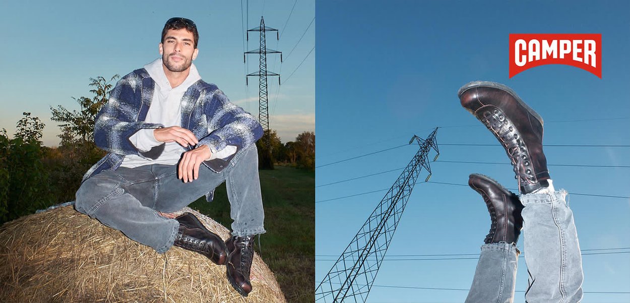 Mann in Freizeitkleidung, der auf einem Heuballen sitzt und schwarze Lederstiefel trägt. Die Stiefel sind erhöht vor dem blauen Himmel mit Stromleitungen zu sehen.