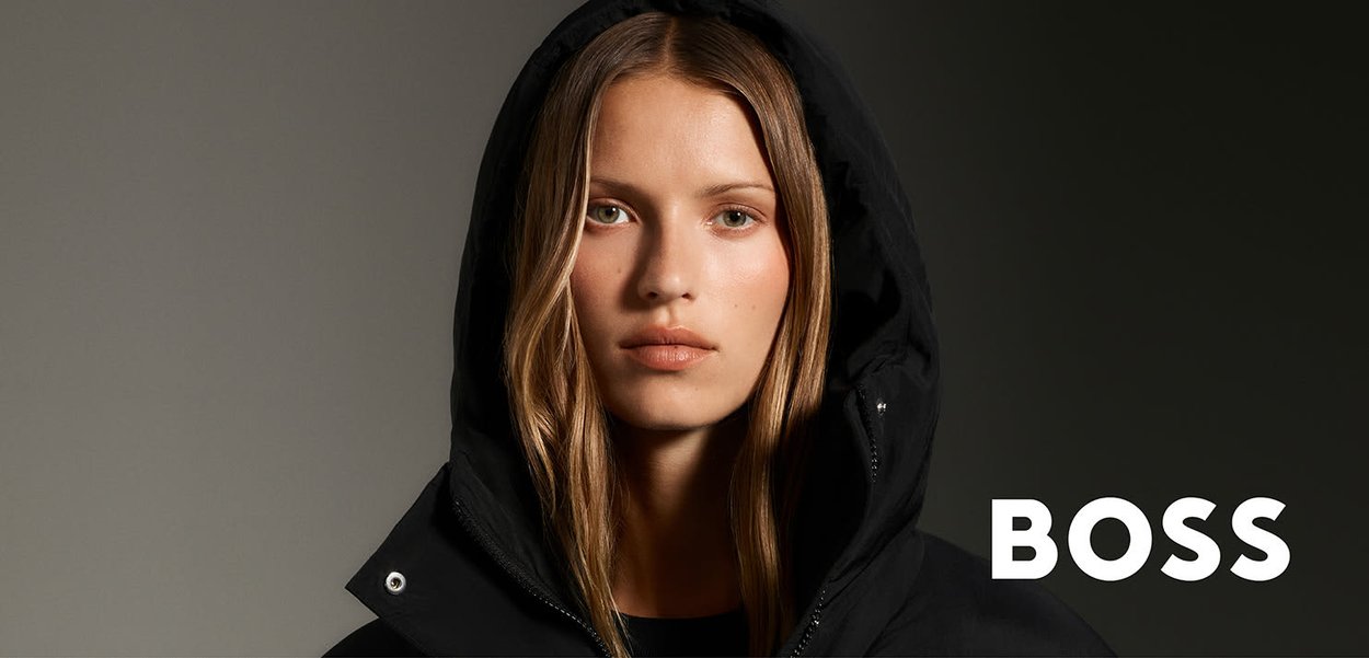 Chaqueta acolchada negra con capucha, cierre de cremallera y tejido texturizado. El modelo está centrado, mostrando rasgos naturales sobre un fondo neutro.