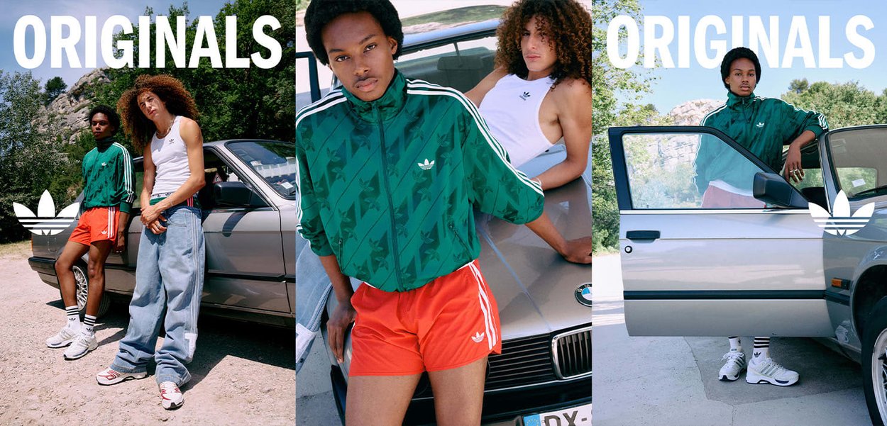 Dos personas con ropa de Adidas Originals posan junto a un coche vintage plateado al aire libre en un día soleado.