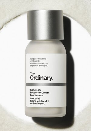 La bottiglia di The Ordinary Sulfur 10% Powder-to-Cream Concentrate con etichetta bianca e cappuccio argentato su una superficie bianca.
