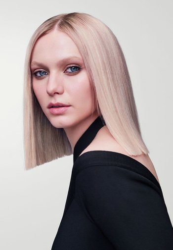 Portrait of a person with straight, light blonde hair, wearing a black off-shoulder top, with blue eyes and a fair complexion.