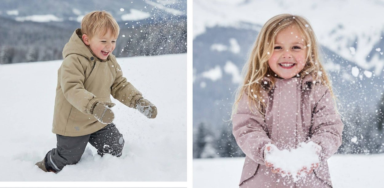 Zwei Kinder spielen im tiefen Schnee; ein Junge kniet und wirft Schnee, während ein Mädchen lächelt und Schnee in den Händen hält.
