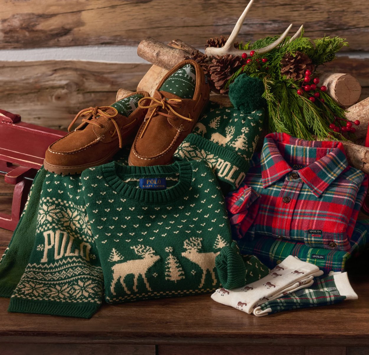 Grønne og røde ternede skjorter, grønne julesweatre med rensdyrmønster og sokker, brune mokkasinsko, vinterhat og festlig dekoration med fyrretræ og bær.