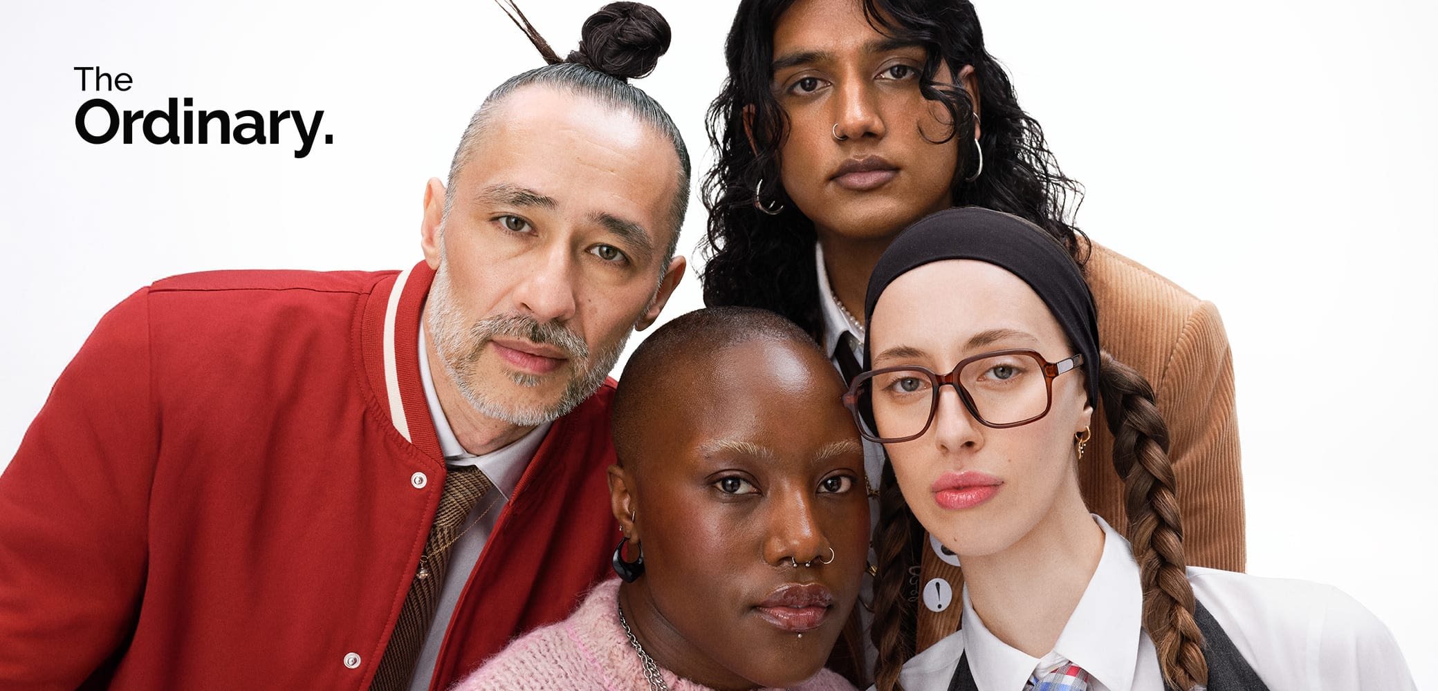 Four individuals pose together, showcasing diverse hairstyles, clothing textures, and accessories. Prominent features include a red varsity jacket, glasses, and a sweater.